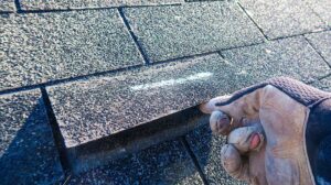 Roof workers inspect dry attic insulation and roof decking above a clean residential ceiling.
