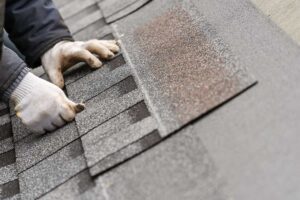 Homeowner safely photographs missing shingles and a ceiling water stain after a storm.