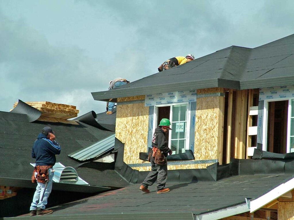 A homeowner examines dark water stains and softened wood decking inside a residential attic.