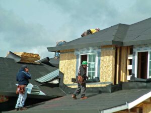 A homeowner examines dark water stains and softened wood decking inside a residential attic.