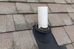 Close view of vented soffits, fascia boards, gutters, and roof shingles along a residential roof edge.