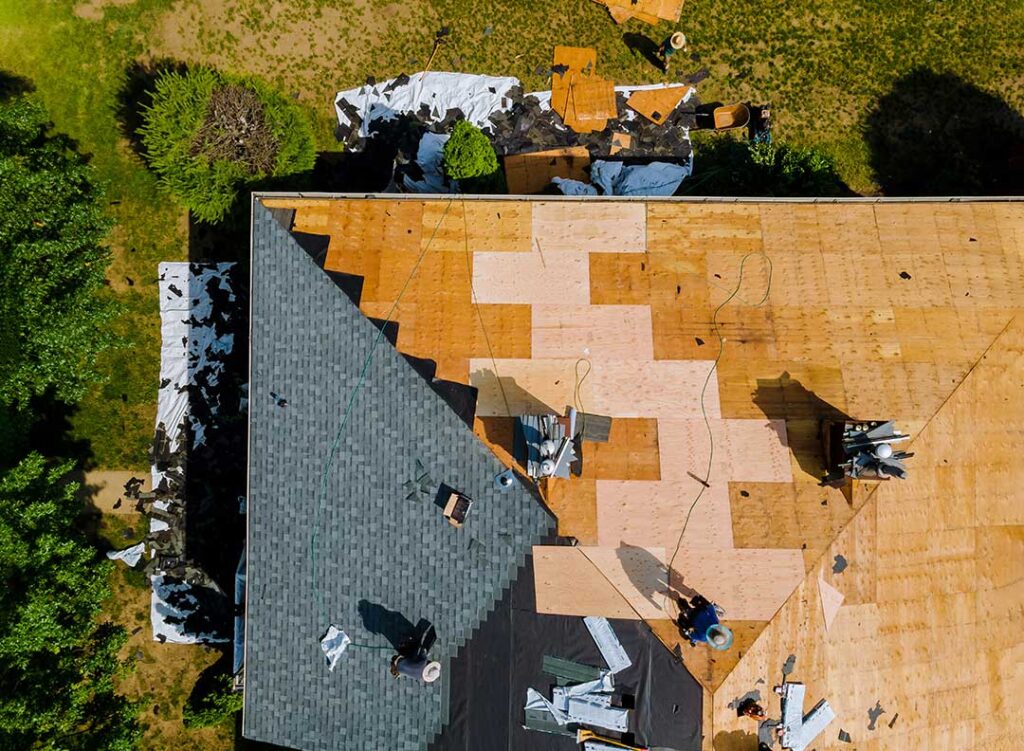 Sunlit asphalt shingles show fading, curled edges, and scattered granules on a residential roof. KEYWORDS: ["sun-damaged asphalt shingles", "roof UV weathering", "residential roof in summer sunlight"]