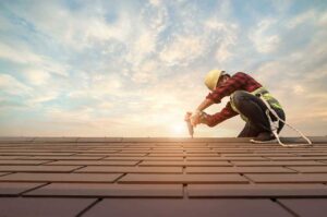 Person in soft-soled shoes carefully crossing a dry shingle roof beside a secured ladder.