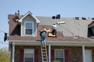 Homeowner reviewing roof warranty papers beside a window while a roof inspection report and photographs rest on the table.