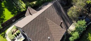 A homeowner examines worn shingles and water stains in a residential attic beneath a sloped roof.